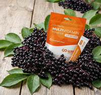 Multivitamin powder package with elderberries on a wooden surface