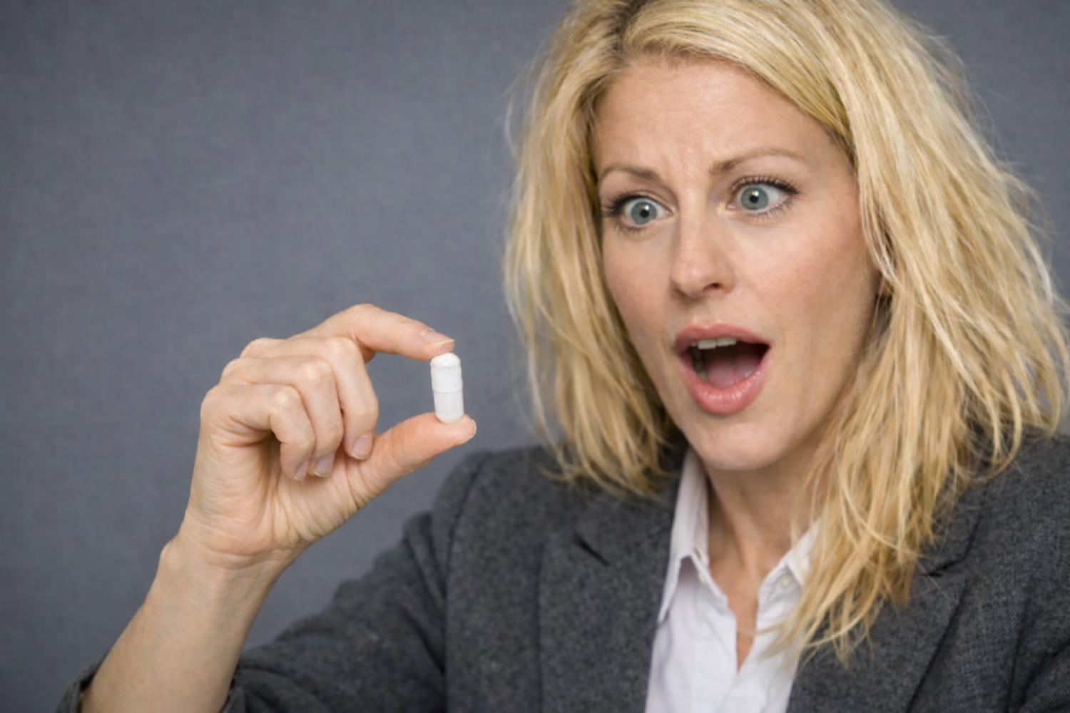 Woman holding a capsule against a gray background